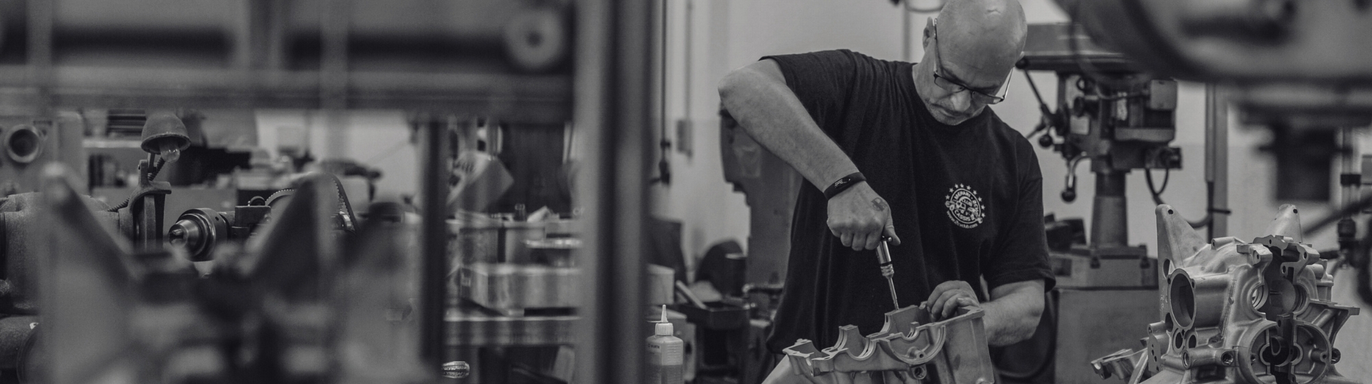 Banniere noir et blanc d'un homme en train de réparer un moteur à la main dans un atelier