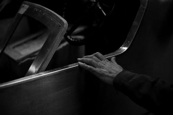 Black and white photo of an antique car door with a man's hand