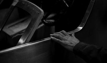 Black and white photo of an antique car door with a man's hand