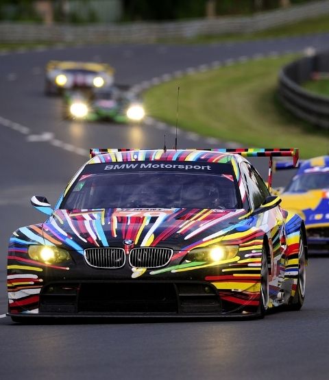 BMW Motorsport colorée en pleine action sur circuit, avec des voitures en arrière-plan.