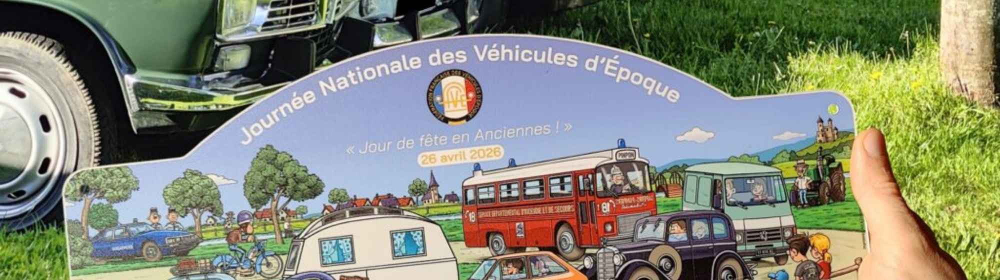 Alignement de voitures anciennes sur pelouse avec une affiche illustrée de la Journée Nationale des Véhicules d’Époque