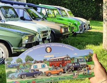 Line of vintage cars on grass with an illustrated poster of the National Vintage Vehicles Day