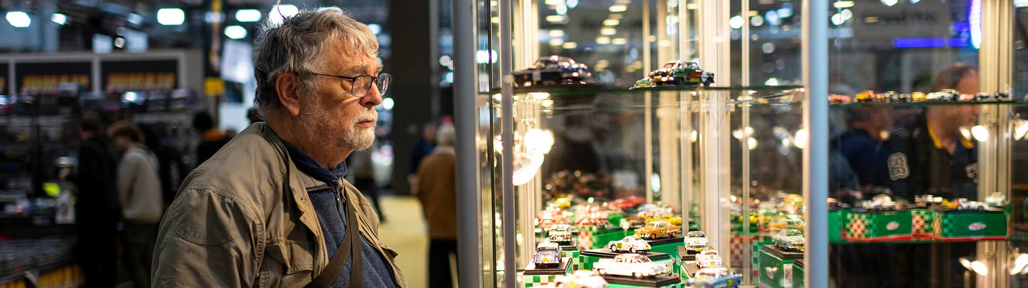 Photo d'un homme regardant pensivement la vitrine d'un exposant à Rétromobile