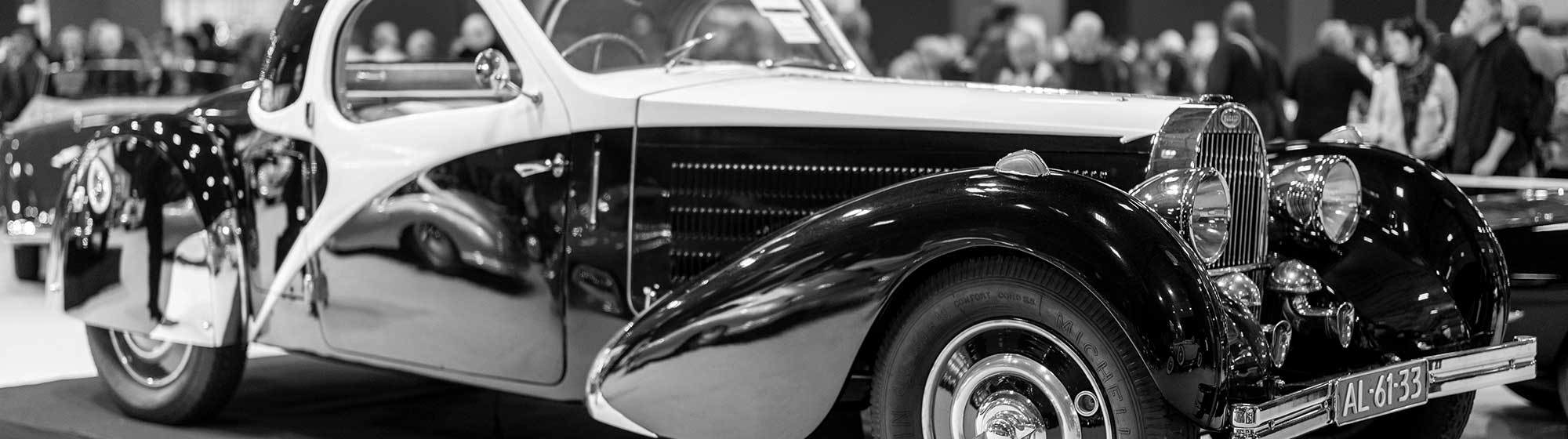Photo d'une voiture de collection en noir et blanc sur le stand d'un exposant à Rétromobile