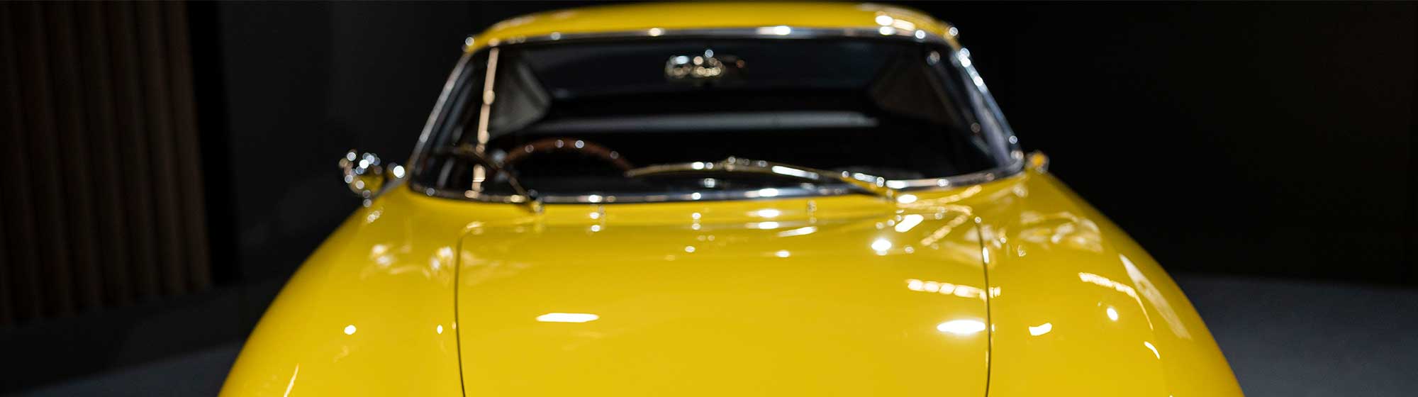 Photo of a yellow vintage Ferrari on display at Retromobile