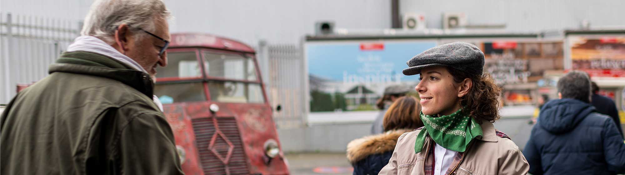 An actress distributing the official guide containing the latest news from the Rétromobile show