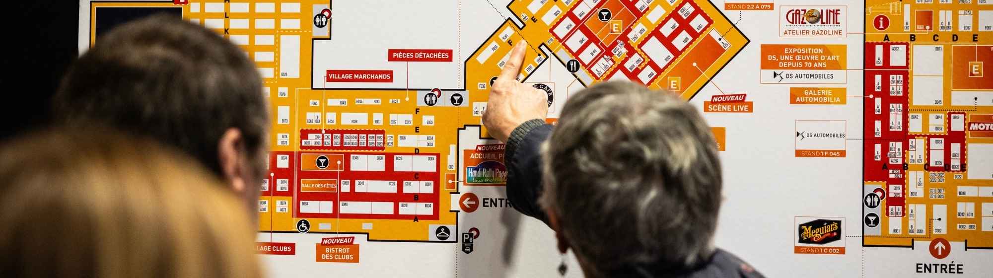 Couple consultant un plan de salon pour s'orienter dans l'espace d'exposition.