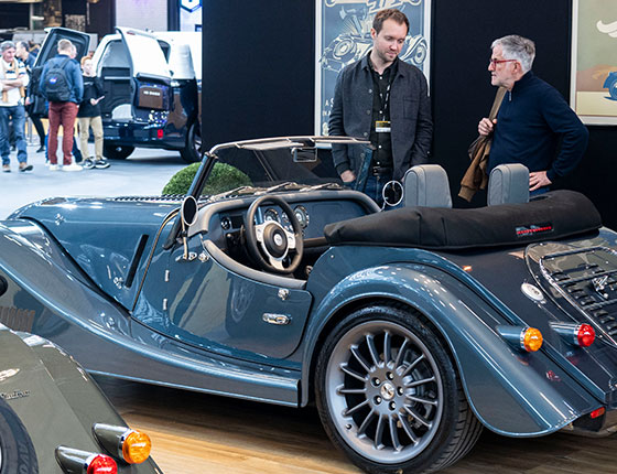 Two men talking in front of a classic vehicle at the Rétromobile show