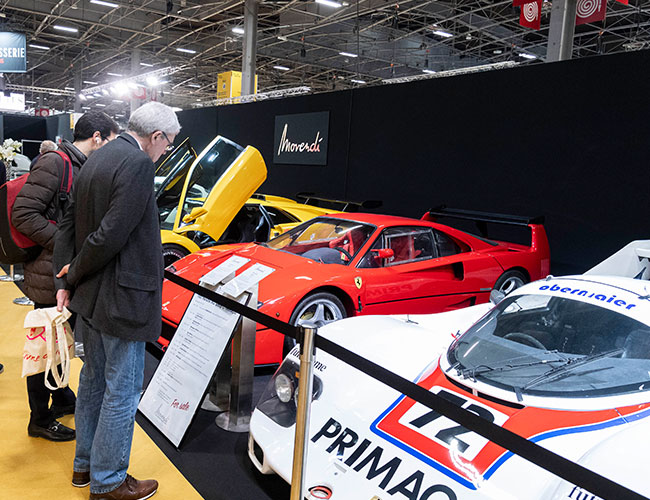 Two men looking at classic cars on a stand at Rétromobile