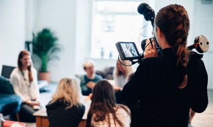 a group of people talking and a woman with a camera films them