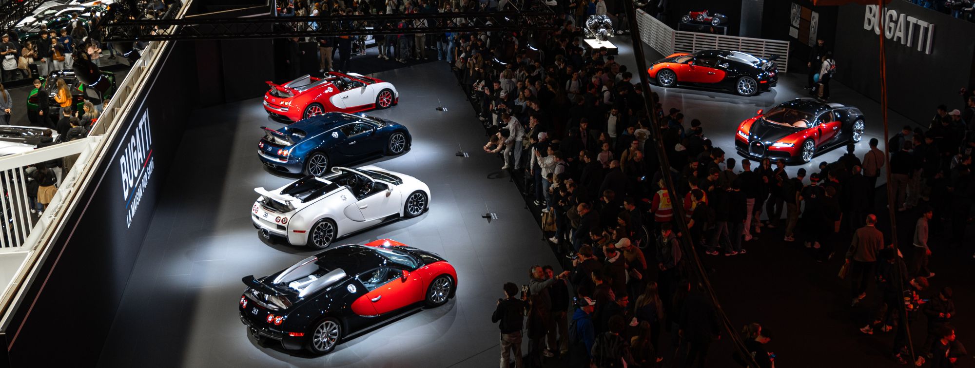 Vue panoramique du stand Bugatti présentant plusieurs voitures de collection lors d’un salon automobile